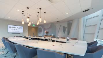 Een vergaderruimte met een lange tafel, stoelen en een bordje waarop staat dat het de Crowne Plaza by IHG is bij Station Utrecht Centraal.