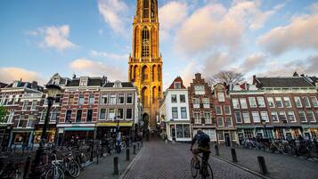 A historic tower with a clock, surrounded by traditional European buildings and a cobblestone street.