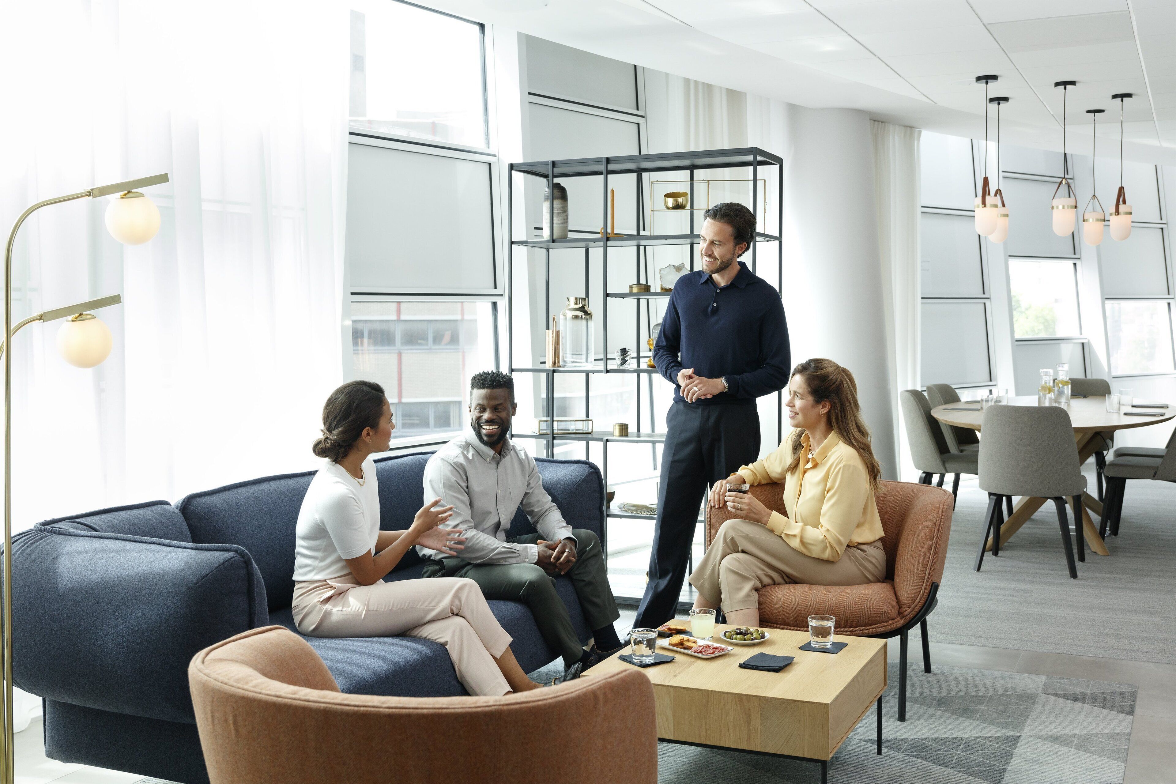A modern office space with a blue sofa, a wooden coffee table, and a glass display cabinet.