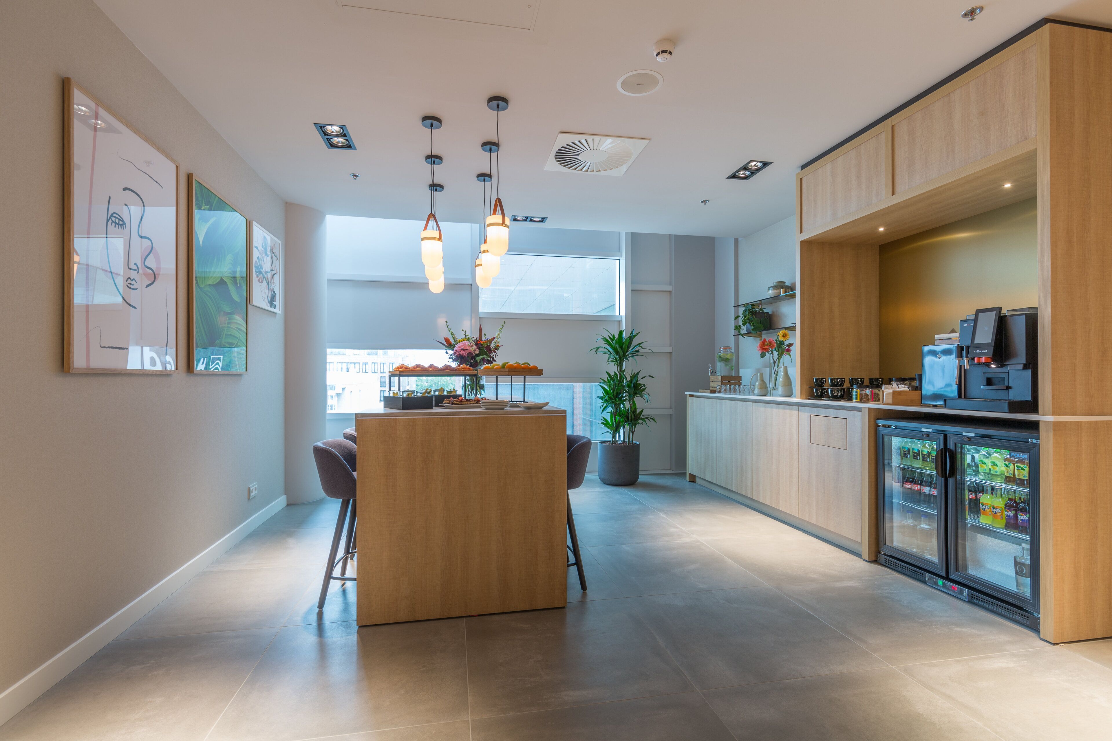 Uma cozinha moderna com ilha central, iluminação pendente e uma geladeira com freezer.