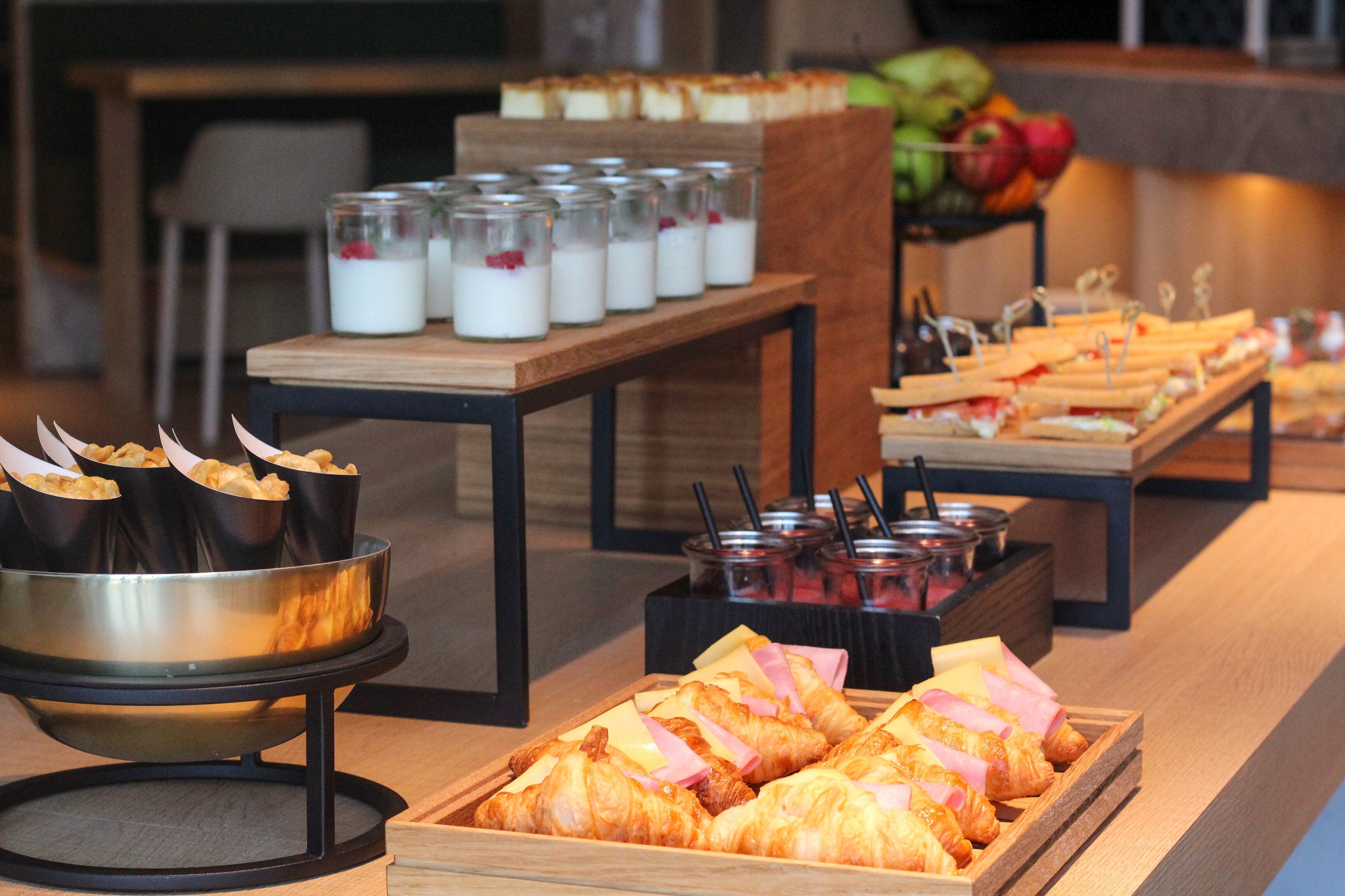 Buffet com diversas opções de comida, incluindo doces, sanduíches e uma seleção de bebidas.