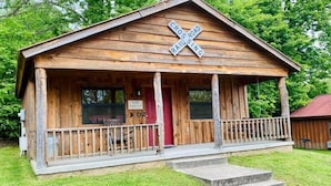A rustic wooden cabin with a porch, a 'Crossing Railroad' sign, and a 'The Depot' sign. - Sylamore Depot Cabin # 302 (Mountain View)