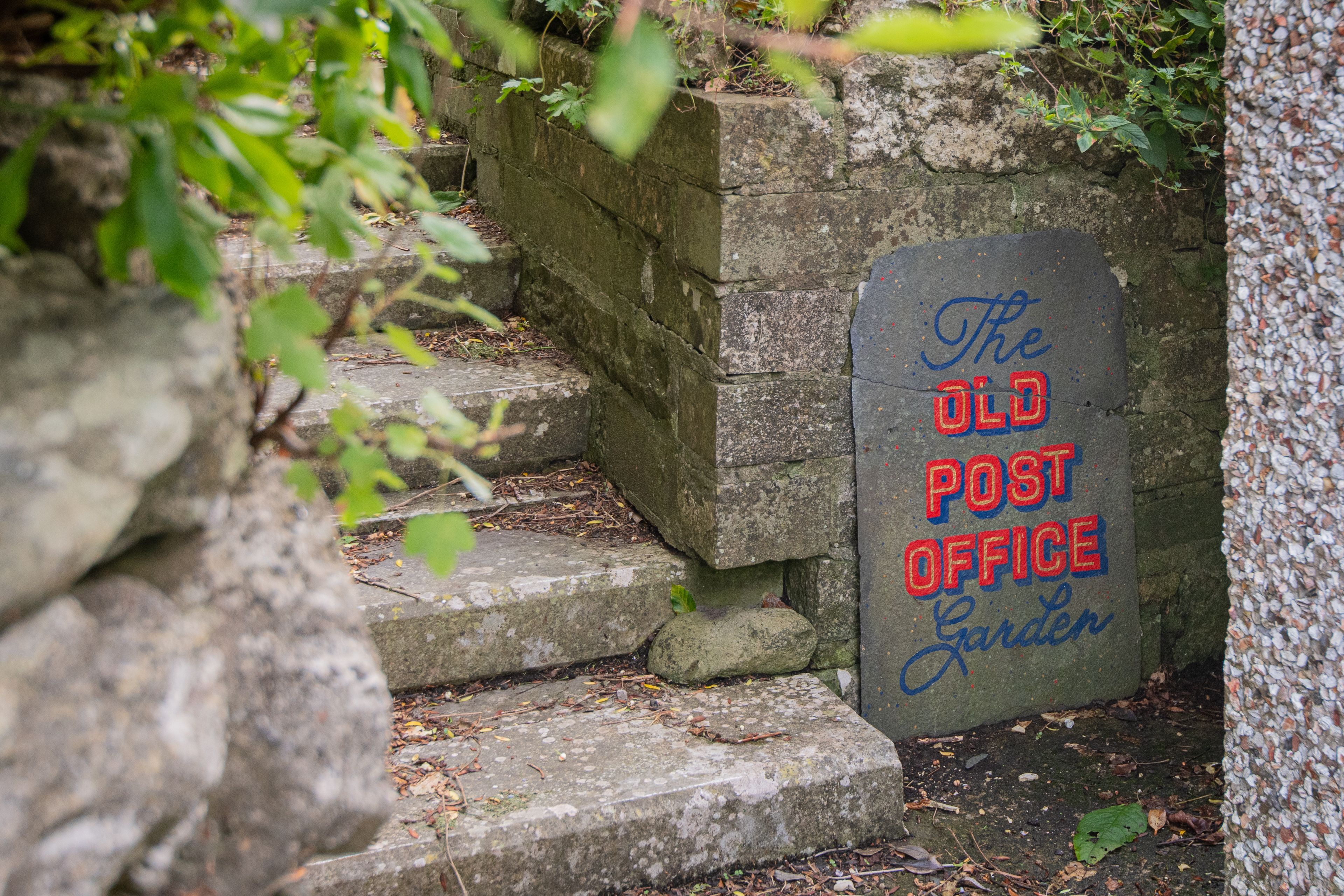 A stone staircase leading to a sign that reads 'The Old Post Office Garden.'