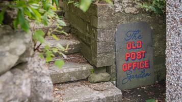A stone staircase leading to a sign that reads 'The Old Post Office Garden.'