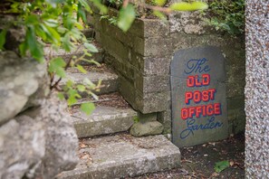 A stone staircase leading to a sign that reads 'The Old Post Office Garden.'