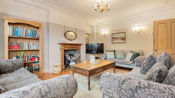 A living room with a fireplace, a television, a bookshelf, and patterned furniture.