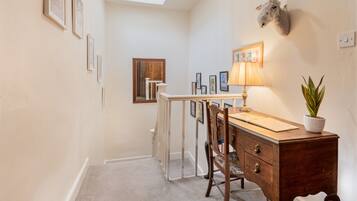 A room with a desk, chair, lamp, and a mounted animal head.