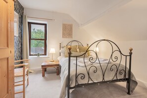 Un dormitorio con una cama, una mesita de noche, una silla, una ventana y una puerta.