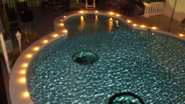 Una piscina circular con desagüe central, bordeada por azulejos e iluminada con pequeñas luces.