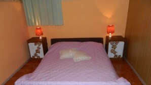 Un dormitorio con una cama individual, dos mesitas de noche, una ventana con cortina azul y un papel pintado decorativo en la pared.