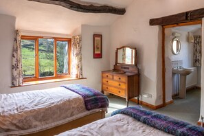 A bedroom with two beds, a dresser, a mirror, and a window with curtains. - High Beckside -  Traditional Lakeland Cottage near Ullswater. Sleeps up to 7 guests (Penrith)