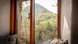 A room with a view of a mountain through a window with wooden frames.