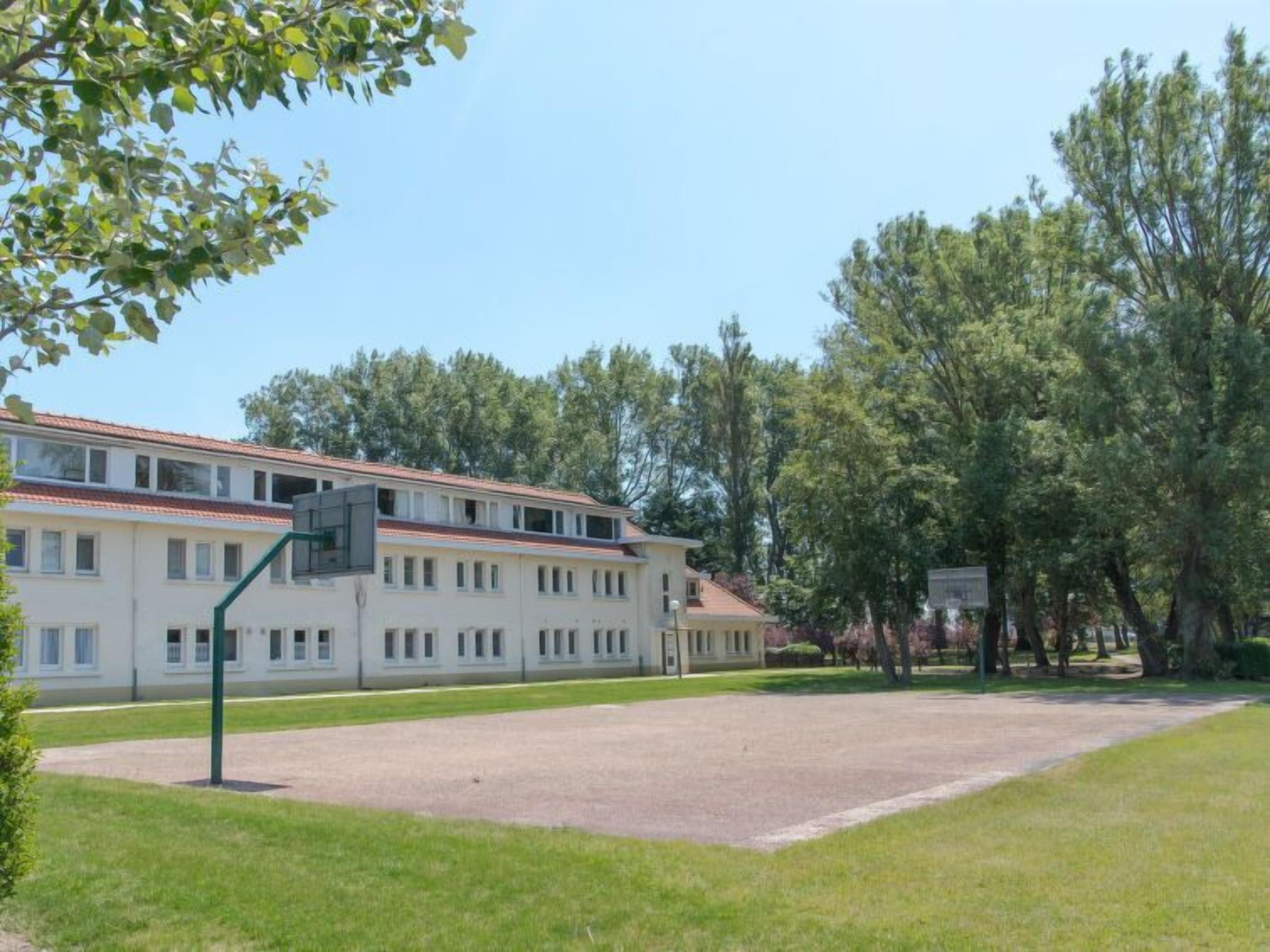 A building with a flat roof, multiple windows, and a basketball court.