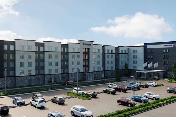 A modern hotel with multiple floors, a parking lot, and a well-maintained landscape.
