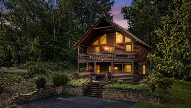 A log cabin with a porch, a staircase, and a stone wall. - ER24 - Honeysuckle Holler | Great Location..Close to town (Pigeon Forge)
