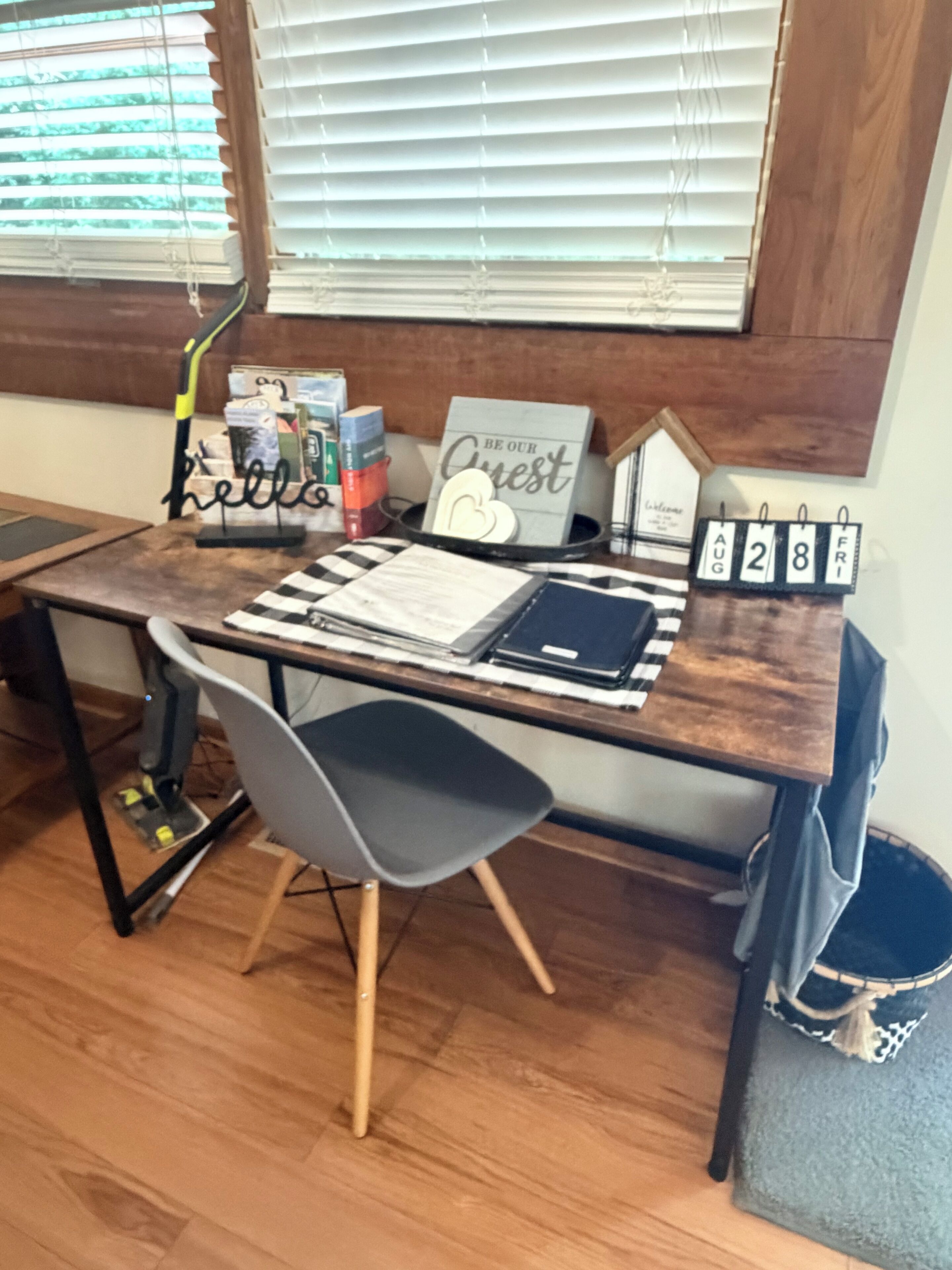 Un bureau en bois avec un ordinateur portable, un calendrier et une pancarte sur laquelle est écrit « Bonjour ».