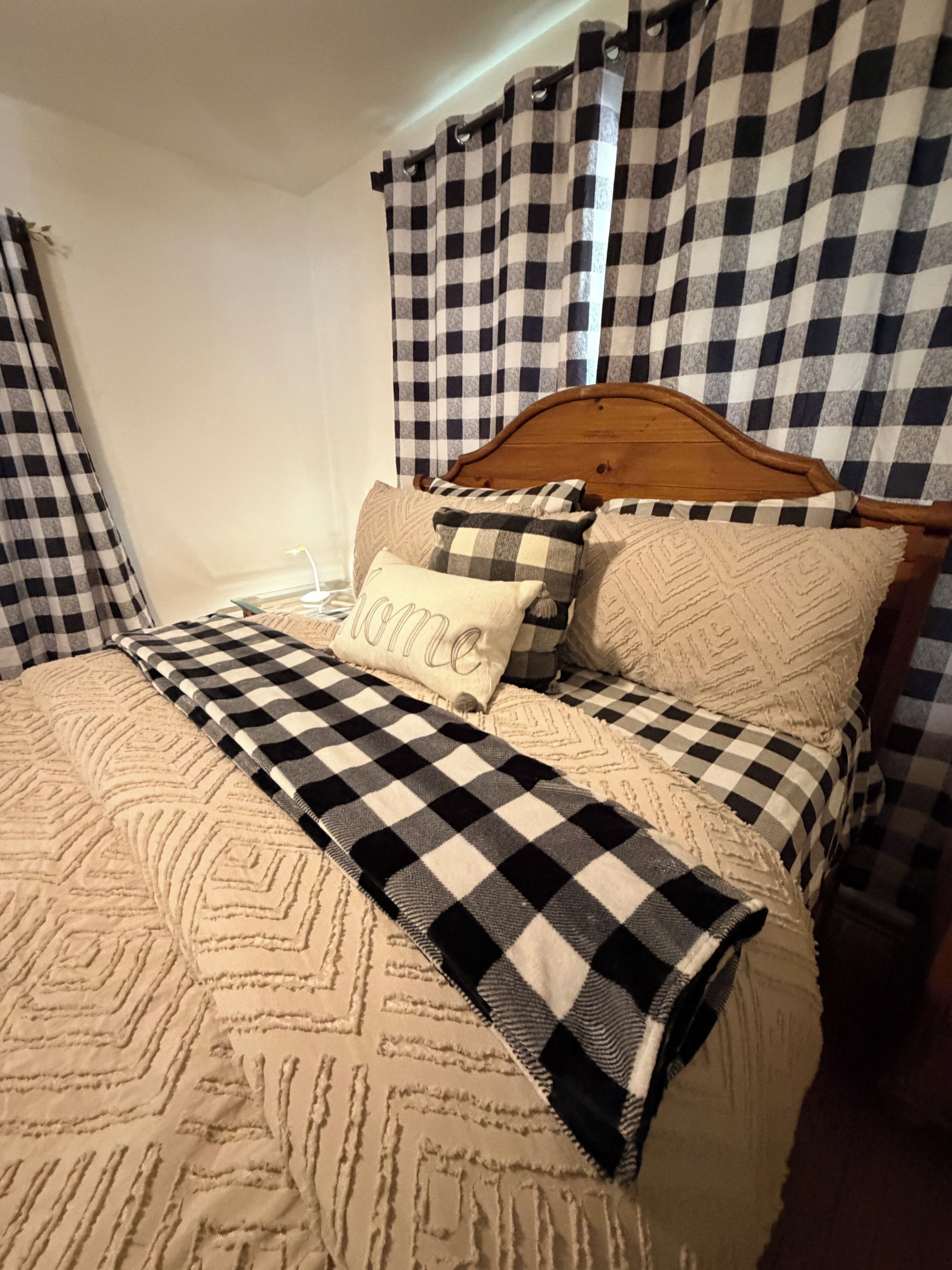 Ein Bett mit karierter Decke, Kissen und einem Kopfteil.