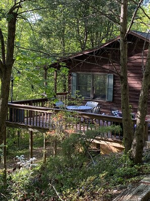 A cabin with a deck, outdoor seating, and a view of the surrounding forest. - Blue Ridge Mountain Air (Old Fort)
