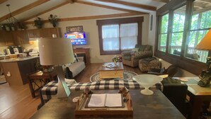 A cozy living room with a wooden dining table, a sofa, and a television. - Blue Ridge Mountain Air (Old Fort)