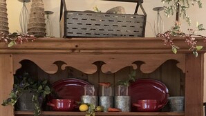 A wooden cabinet with shelves holding red ceramic dishes, glass containers, and a wooden bowl with flowers. - Blue Ridge Mountain Air (Old Fort)