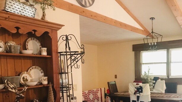 A cozy living room with wooden beams, a dining area with a table and chairs, and a large window. - Blue Ridge Mountain Air (Old Fort)