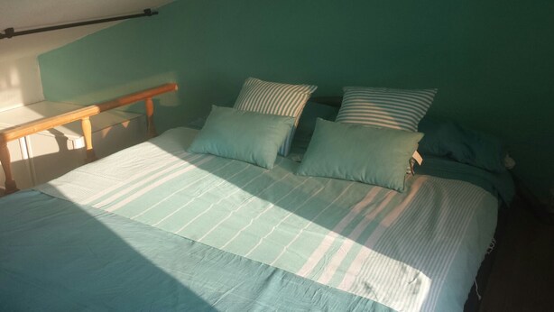 Uma cama com colcha listrada, duas almofadas e cabeceira de madeira.