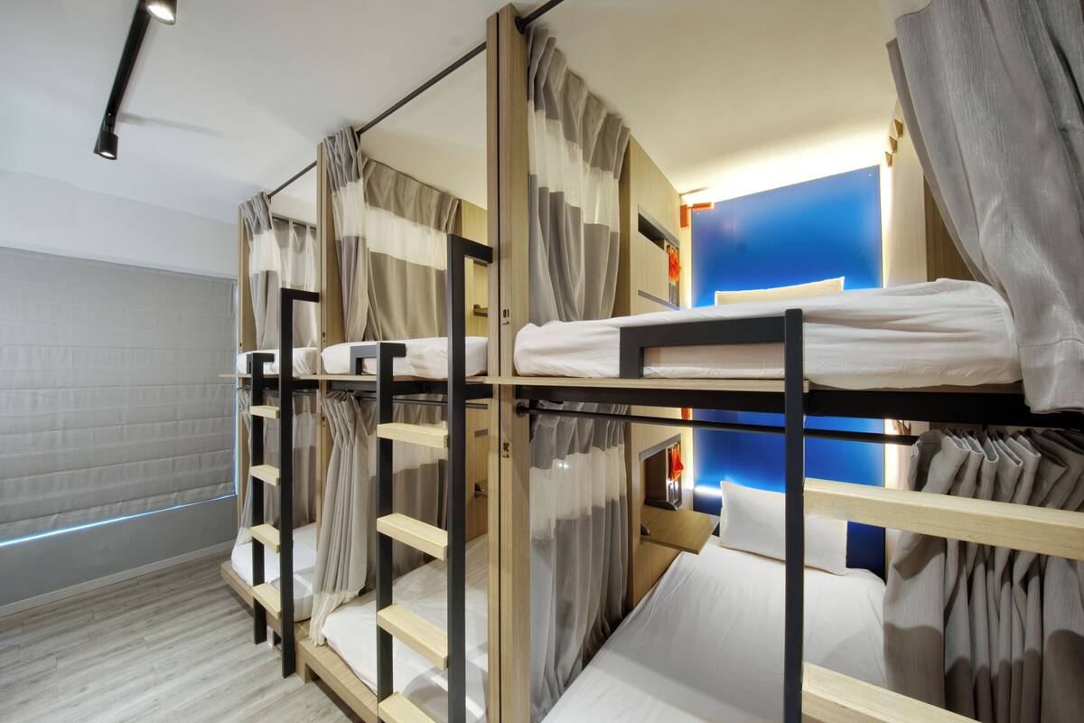 A bunk bed room with curtains, a mirror, and a blue wall.