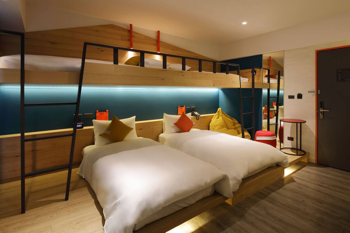 A bunk bed room with a ladder, two beds, and a small table.