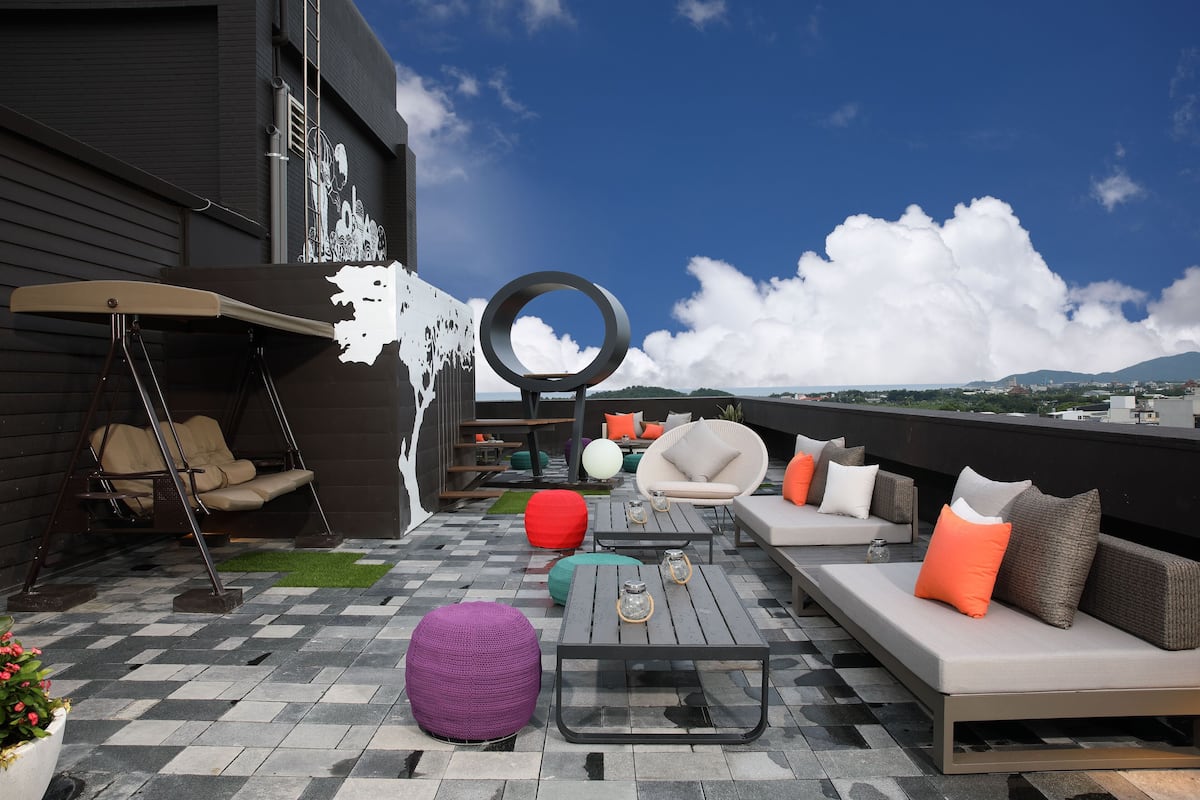 A rooftop patio with a swing chair, round seating, a sofa set, and a coffee table.