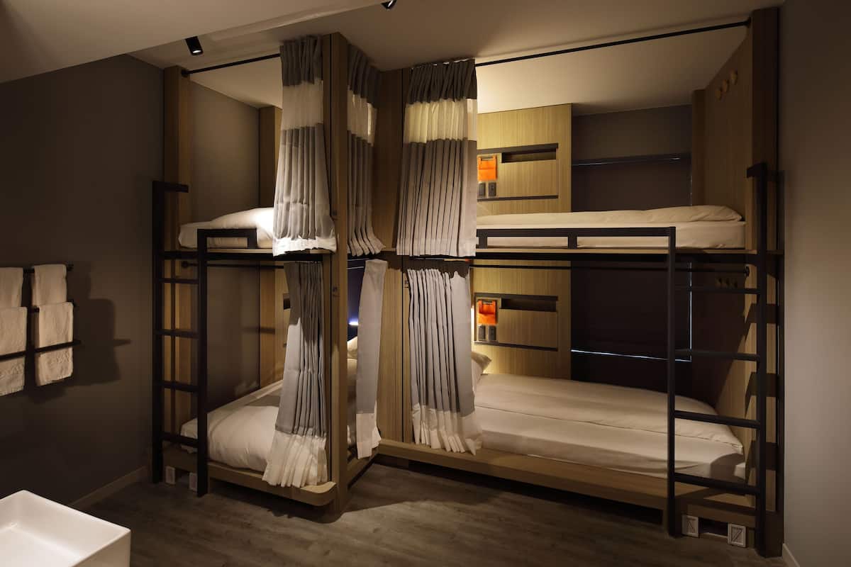 A bunk bed room with a wooden headboard, a bedside table, and a curtain.