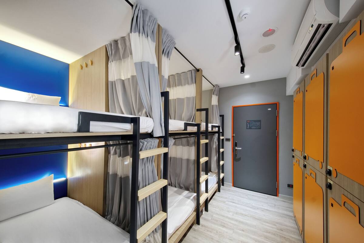 A hotel room with bunk beds, a wardrobe, and a door with a sign.