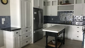 Una cocina moderna con armarios blancos, encimera negra y salpicadero de azulejos.