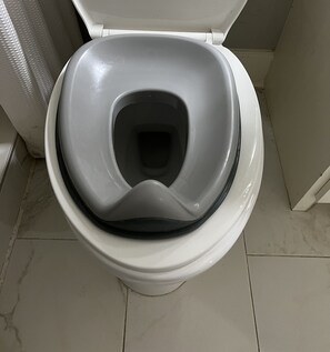 Eine Toilette mit weißem Sitz und Deckel, einer schwarzen Schüssel und einem gefliesten Boden.