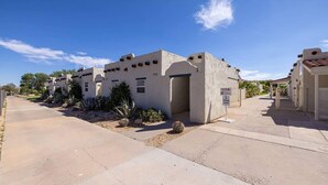 A residential area with stucco buildings, a paved driveway, and landscaped gardens.