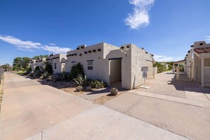 A residential area with stucco buildings, a paved driveway, and landscaped gardens.