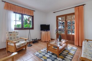 A living room with a sofa, a coffee table, a TV, and a door with glass panels.