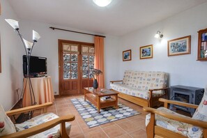 A living room with a sofa, a wooden coffee table, a television, a fireplace, and a patterned rug.