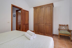 A bedroom with a bed, a wooden wardrobe, and a wooden chair.