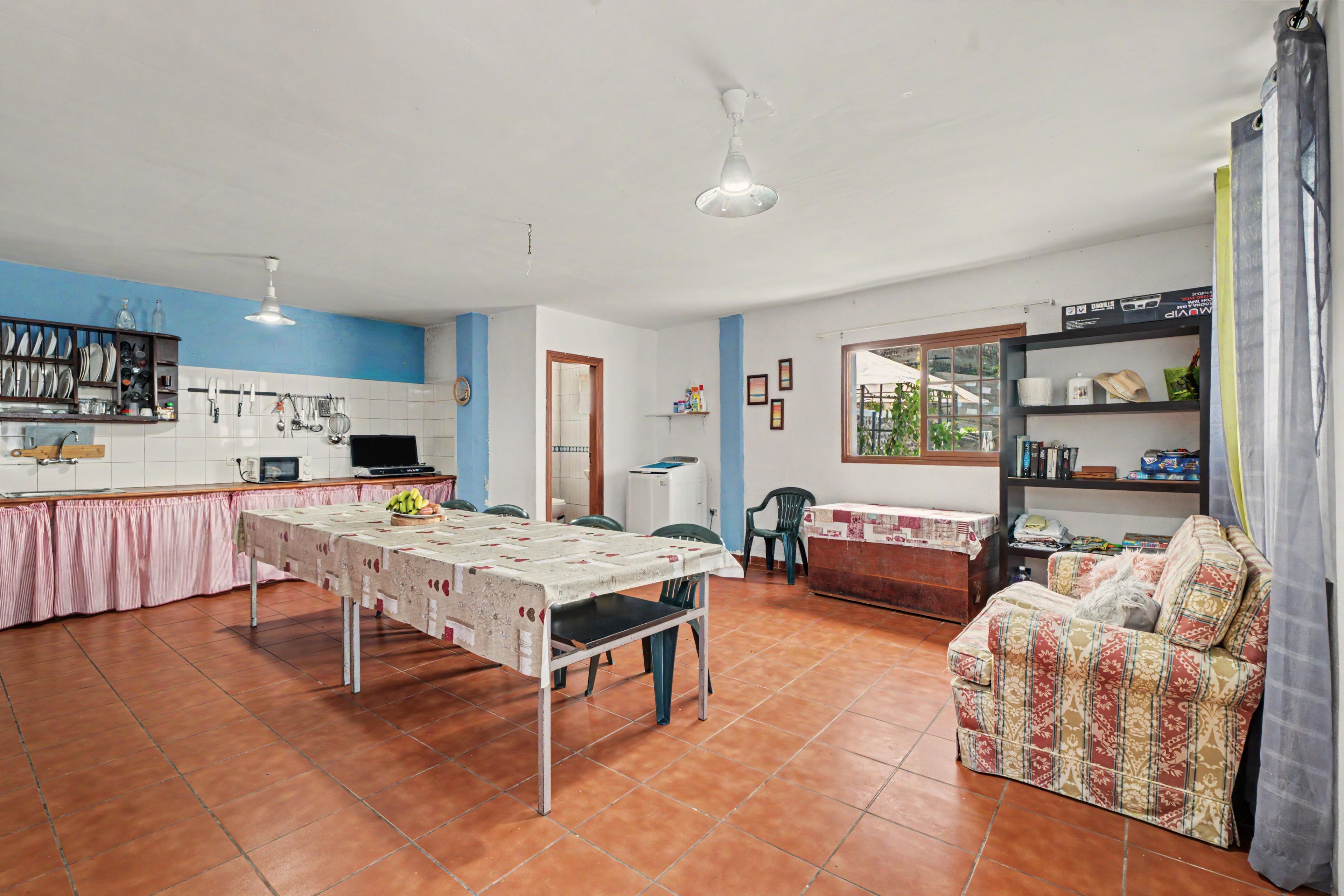 A spacious living area with a dining table, kitchen, and a sofa.