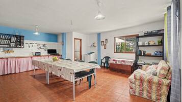 A spacious living area with a dining table, kitchen, and a sofa.
