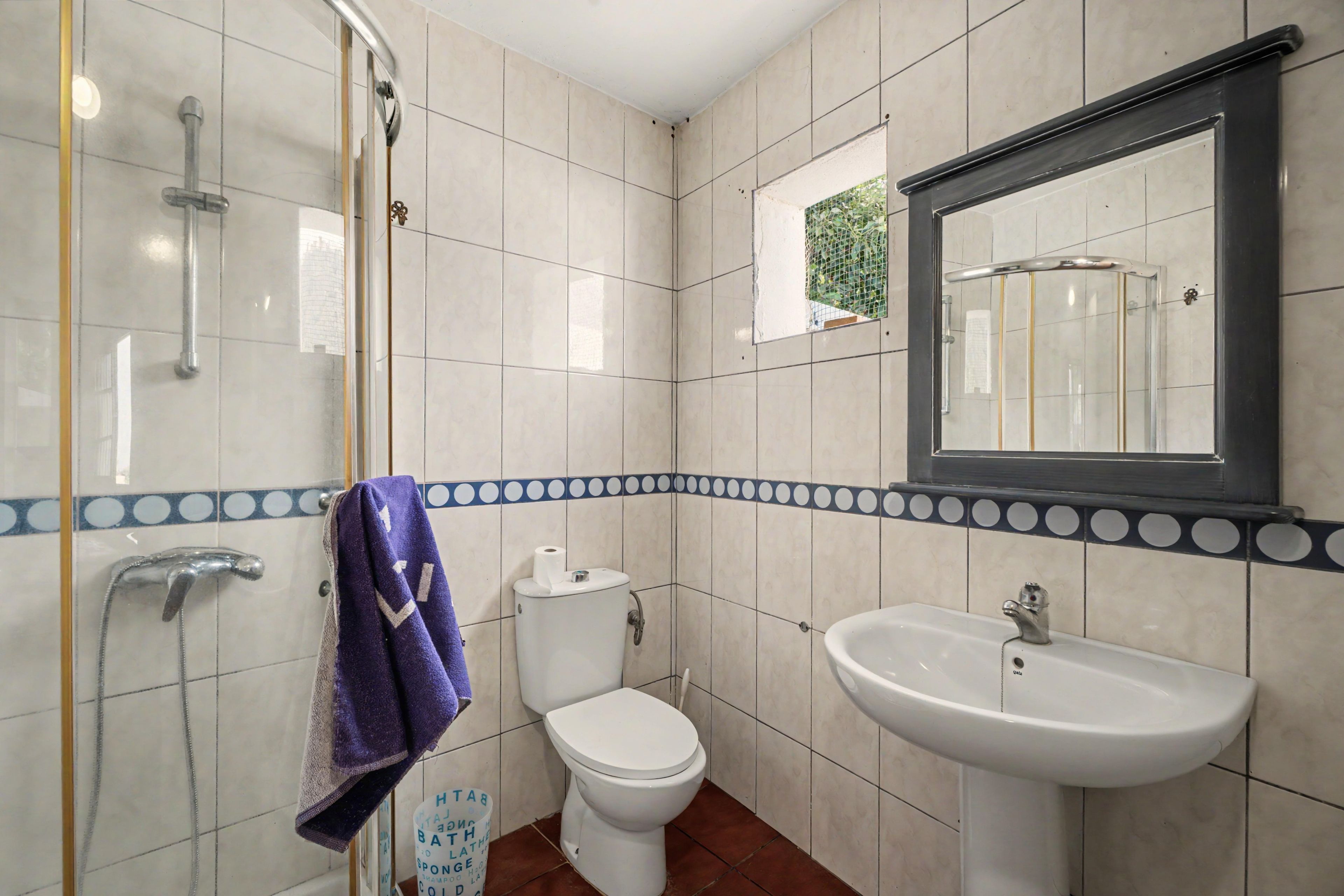 A bathroom with a shower, toilet, sink, and a mirror.