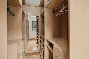 A narrow walk-through closet with multiple shelves and hanging space.