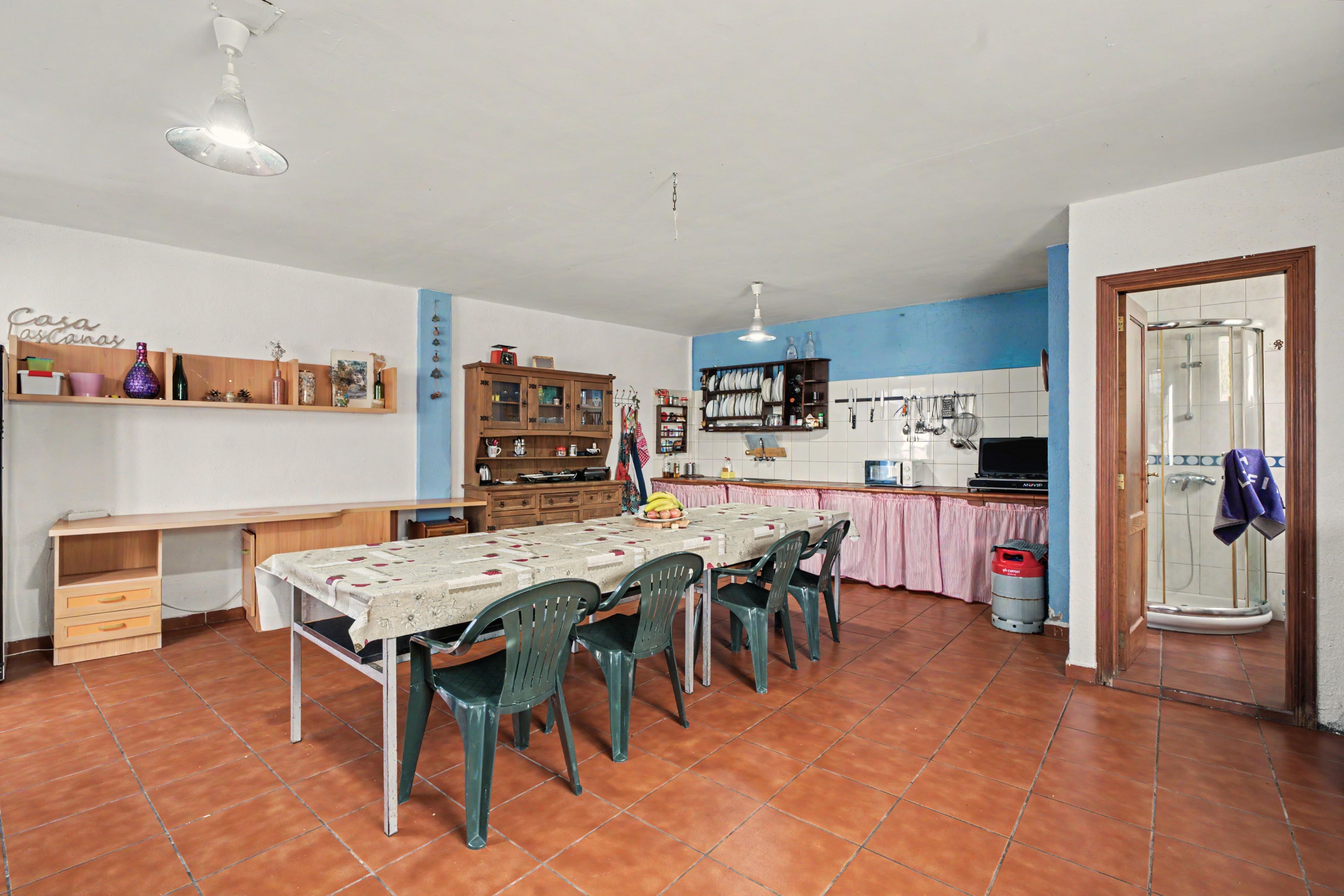 Een ruime keuken met een eettafel, stoelen en diverse keukenapparaten.