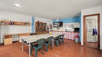 Een ruime keuken met een eettafel, stoelen en diverse keukenapparaten.