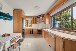 Una cocina con armarios de madera, horno empotrado y ventana con vistas al verdor.