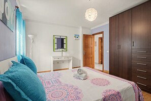 A bedroom with a bed, a dresser, a mirror, and a wardrobe.