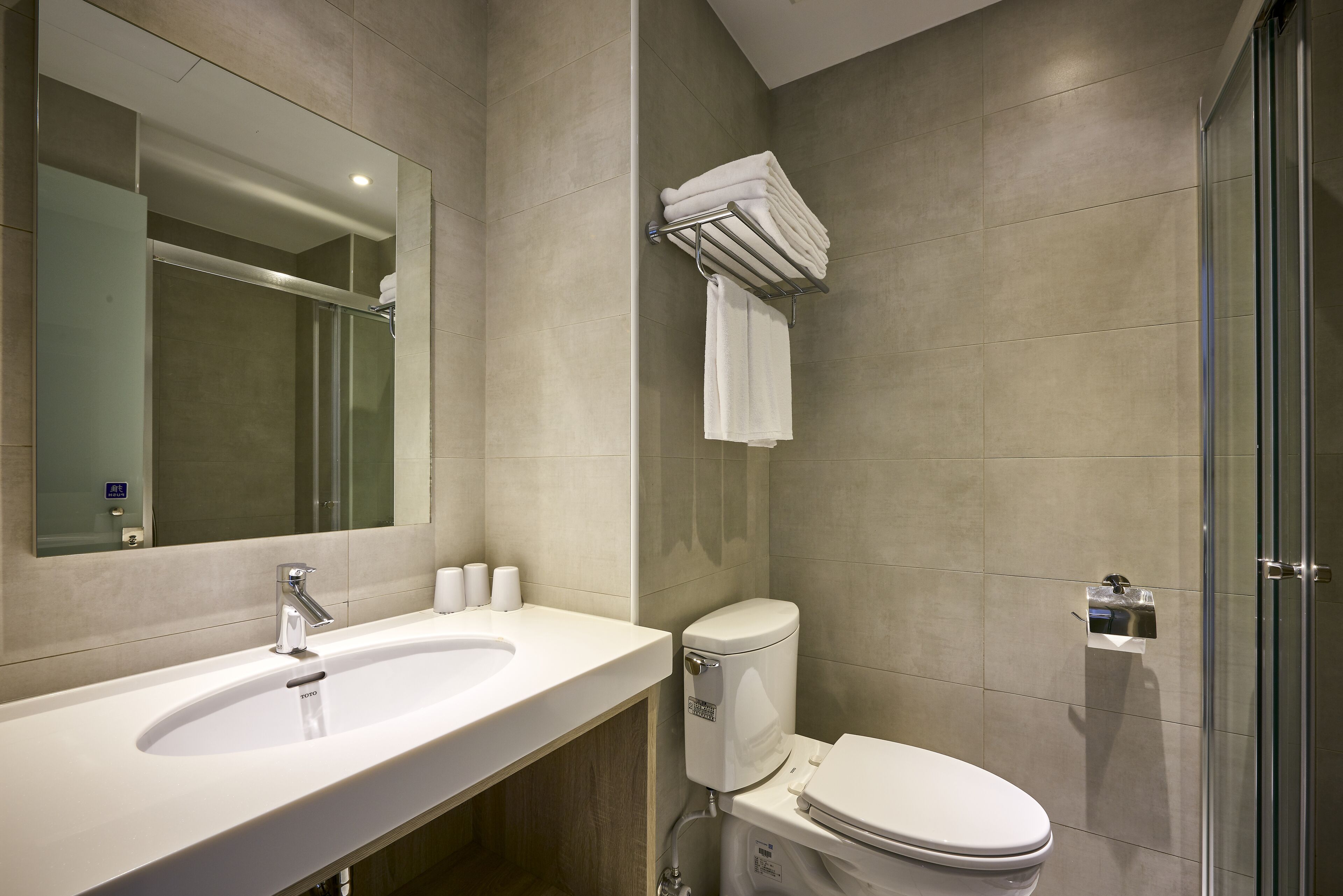A modern bathroom with a sink, toilet, and glass shower enclosure.