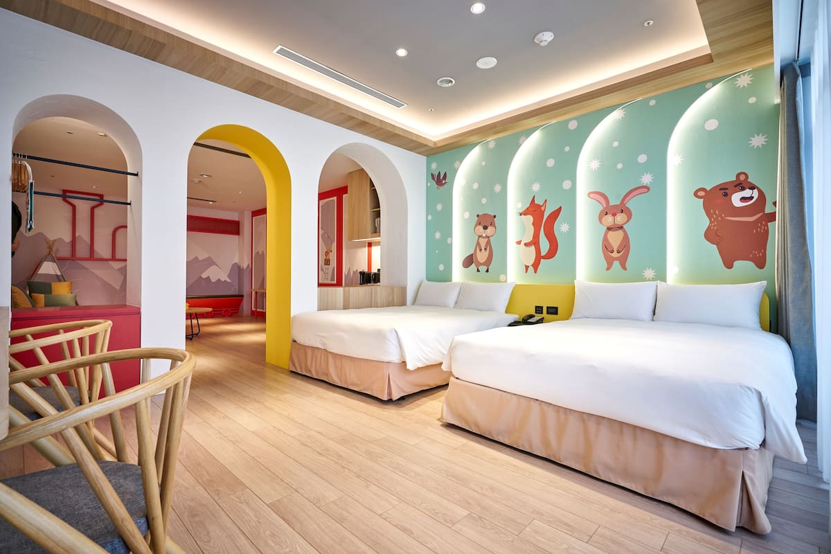A modern hotel room with two beds, wooden flooring, and a colorful mural on the wall.