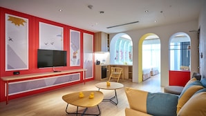 Una sala de estar moderna con televisión de pantalla plana, comedor y cocina.
