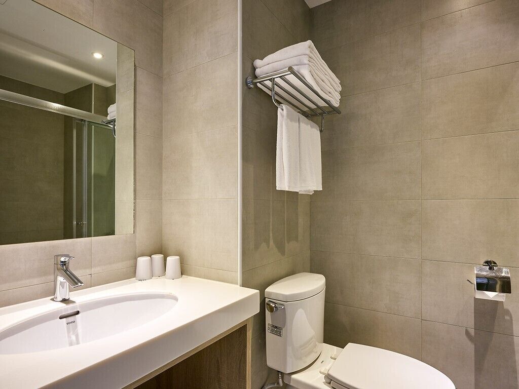 A modern bathroom with a large sink, toilet, and a towel rack.
